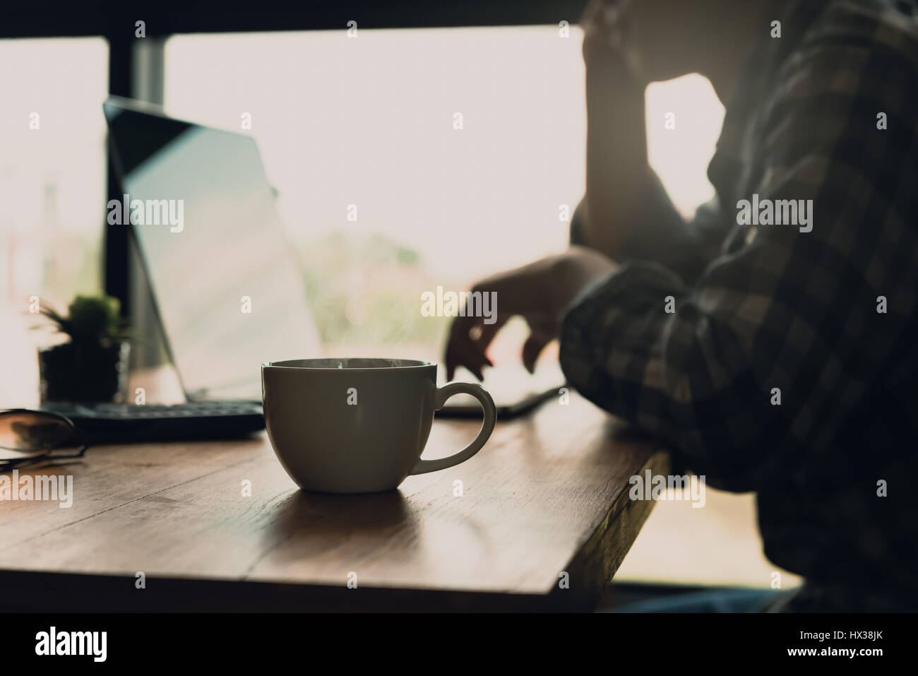 Unschärfe des Mannes zu Hause online arbeiten oder Online-Nebenjobs mit Kaffeetasse auf dem Schreibtisch. Fügen Sie Filter dunklen Ton für müde fühlen oder dazu führen, dass sich in n Stockfoto