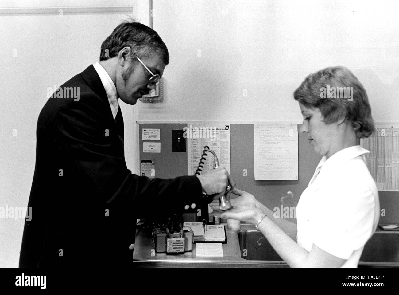 Inspekteur des Atomic Energy Commission untersucht die Hände der Nuklearmedizin Techniker für radioaktive Kontamination, 1975. Bild mit freundlicher Genehmigung US Department of Energy. Stockfoto