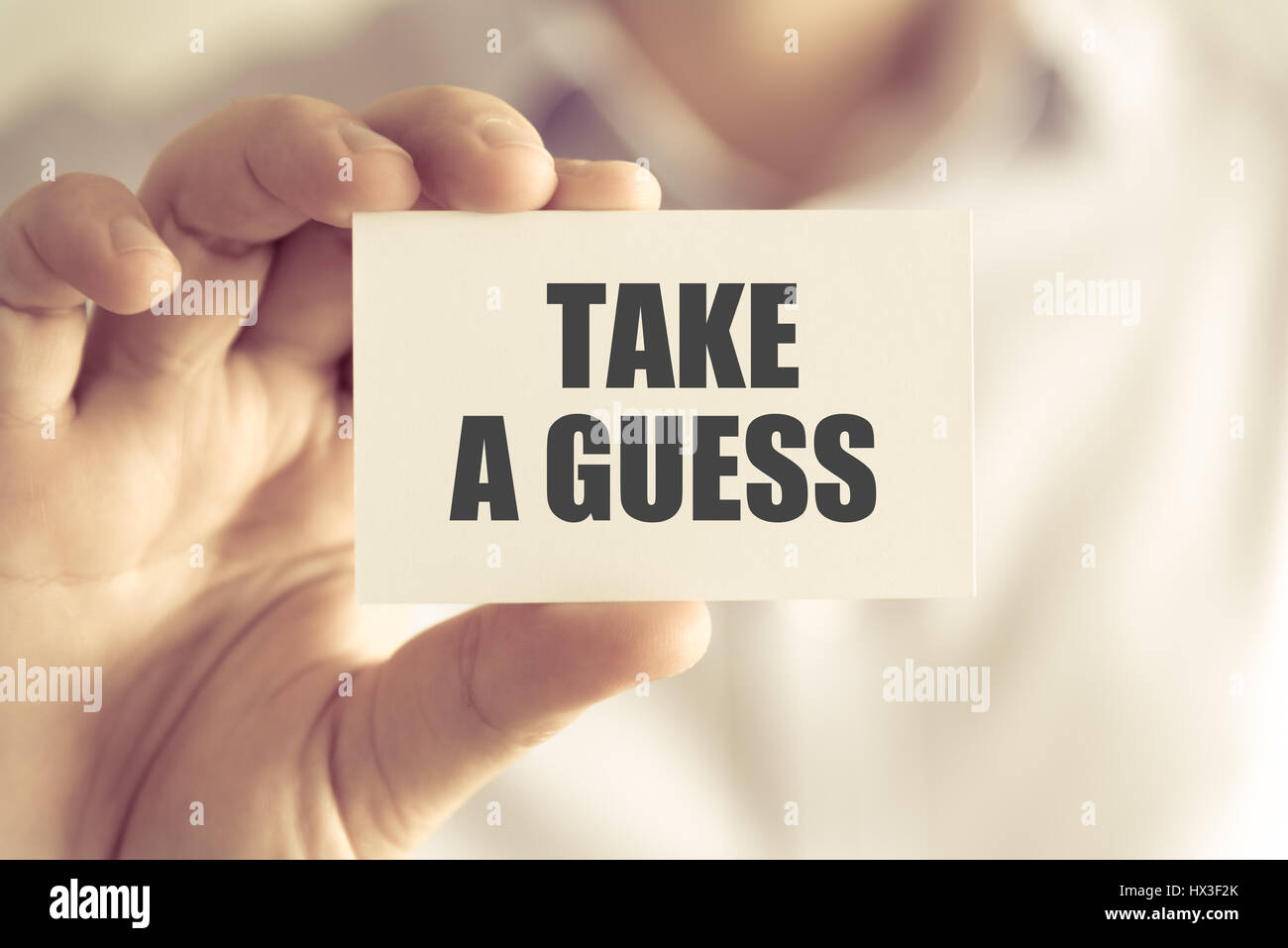 Closeup auf Geschäftsmann hielt eine Karte mit Text nehmen A GUESS, Firmen-Konzept-Image mit soft-Fokus-Hintergrund und Vintage-Ton Stockfoto