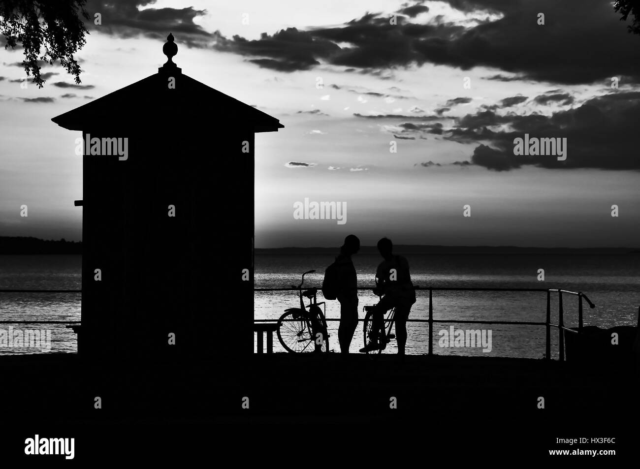 Zwei Silhouetten von jungen mit Fahrräder hängen zusammen am Meer Stockfoto