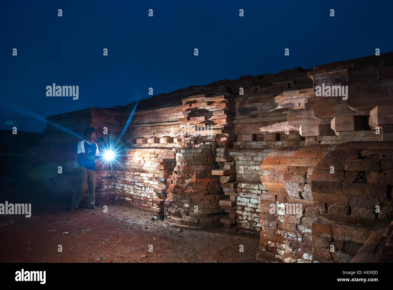 Ein Einheimischer, der während seiner Wiederaufbauzeit in Karawang, Indonesien, eine Taschenlampe zur Wand des Blandongan-Tempels benutzte. Stockfoto