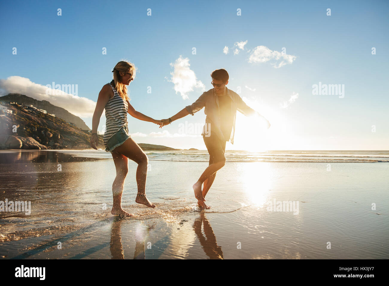 Voller Länge Schuss junges Paar Hand in Hand am Strand gehen und Spaß haben. Junger Mann und Frau genießen Ferien am Ufer Meeres. Stockfoto