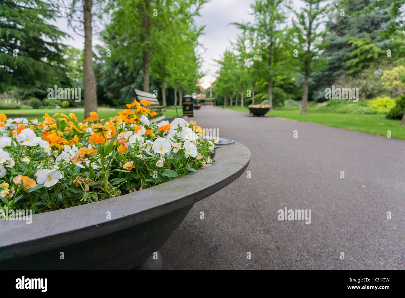 Pflanzgefäße in einem Park voller Blumen auf einem Pfad Stockfoto