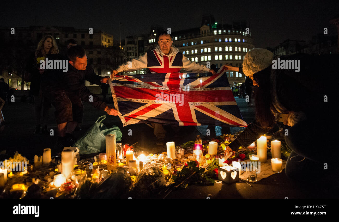 Ein Mann namens John Loughrey Union Jack mit einem Zitat drauf vor Kerzen auf eine Kerze hält beleuchtet Mahnwache gehalten zu Ehren der Opfer des Westminster-Terror-Anschlag. Stockfoto