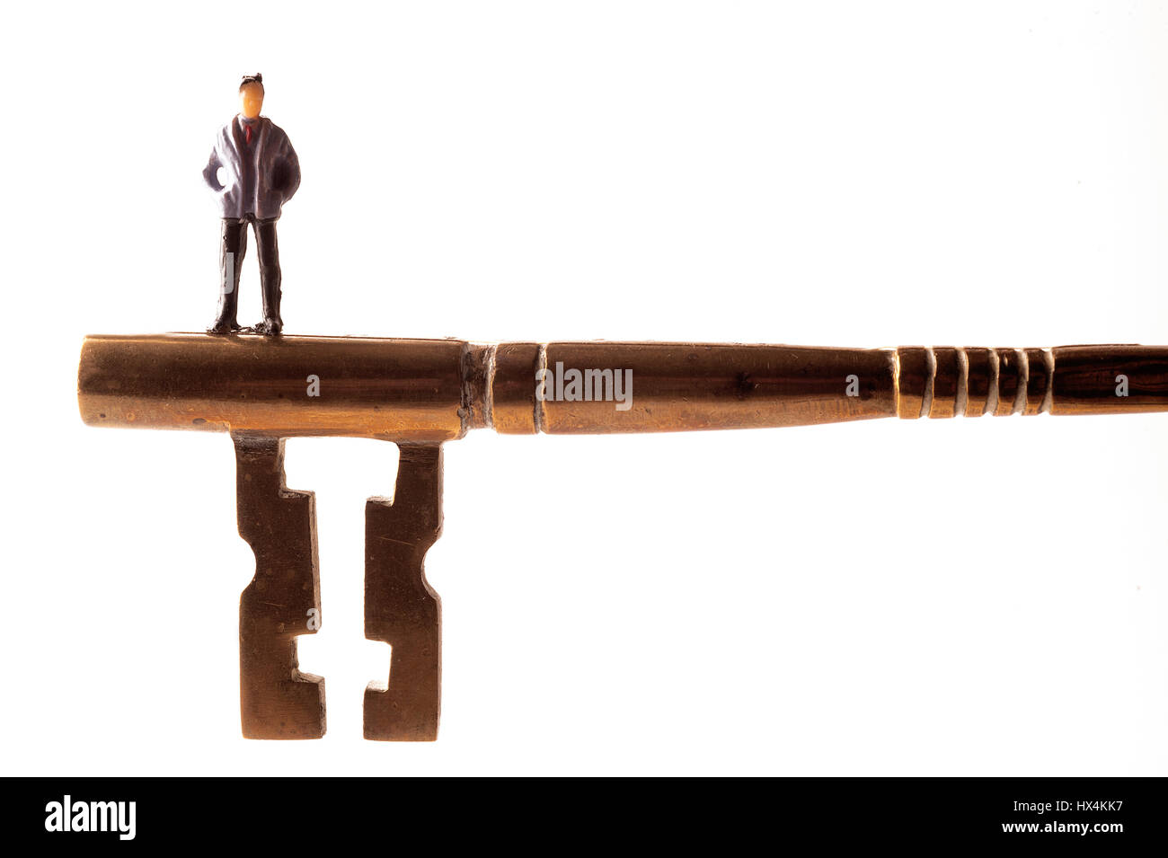 Miniatur Figur eines Mannes steht auf riesige Messing Schlüssel vor weißem Hintergrund Stockfoto