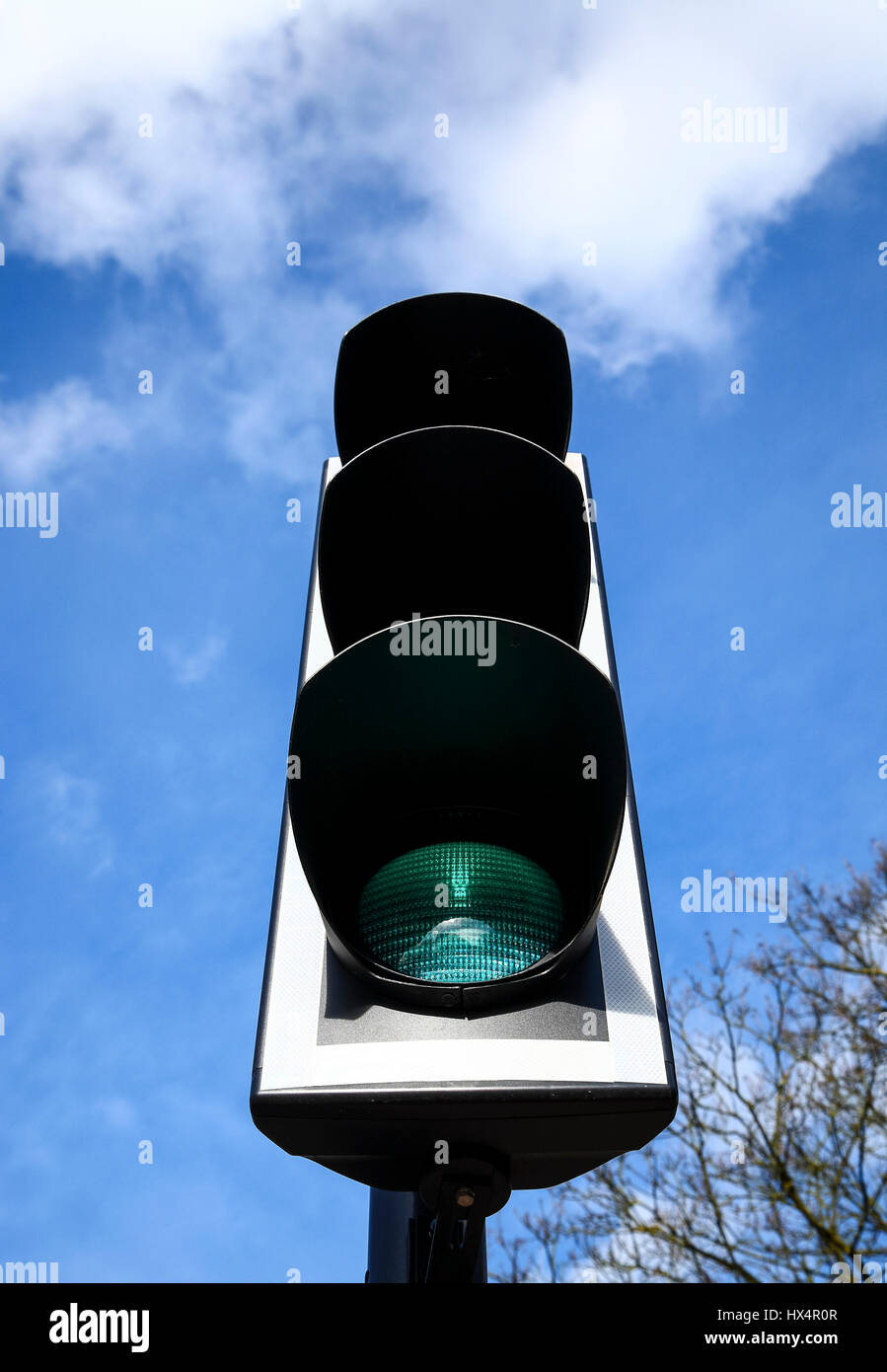 Nahaufnahme von UK-Ampel zeigt ein grünes Licht mit einem blauen Himmelshintergrund Stockfoto