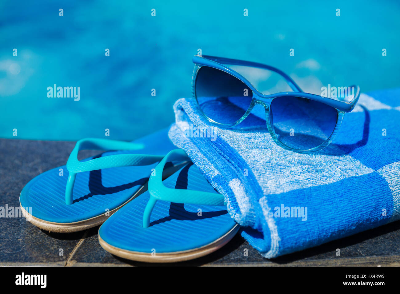 Blaue Pantoffeln und Sonnenbrillen in der Nähe von Schwimmbad - Ferienkonzept Stockfoto