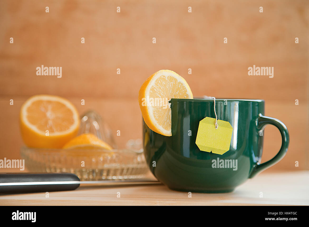 Tasse Tee mit Zitrone in Scheiben geschnittene Zitrone mit Entsafter auf einem hölzernen Hintergrund. Stockfoto