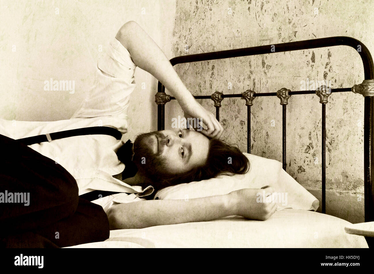 Retro-Mann im Zweifelsfall auf Bett Stockfoto