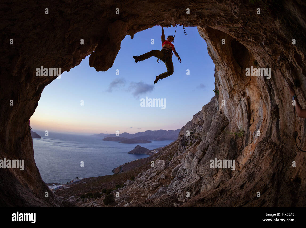 Weibliche Kletterer greifen Haltegriff an Decke in Höhle Stockfoto
