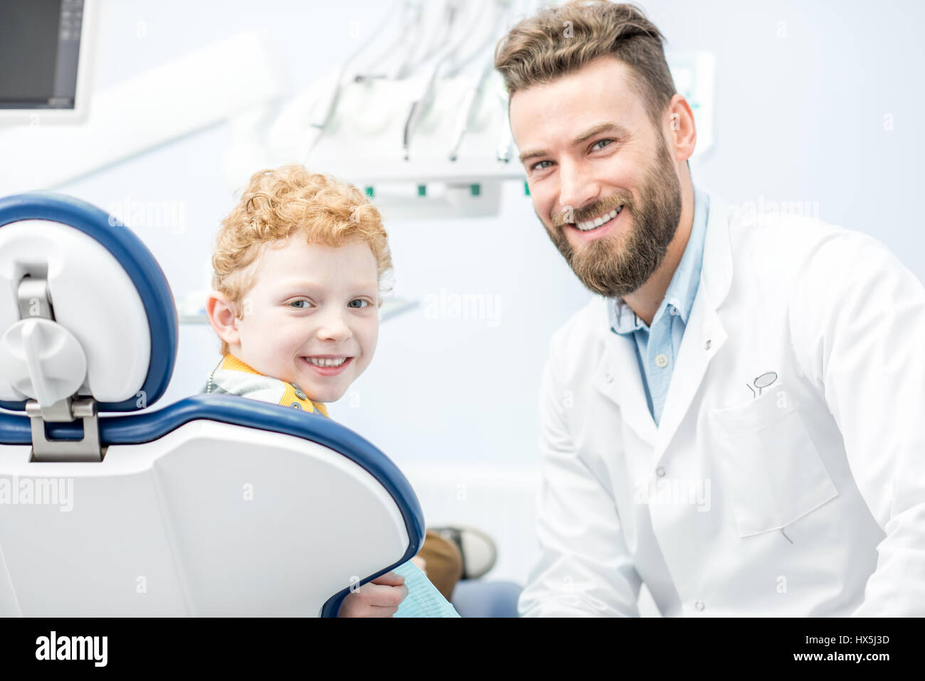 Porträt des schönen Zahnarzt und fröhlicher Junge auf dem Stuhl in der zahnärztlichen Praxis Stockfoto