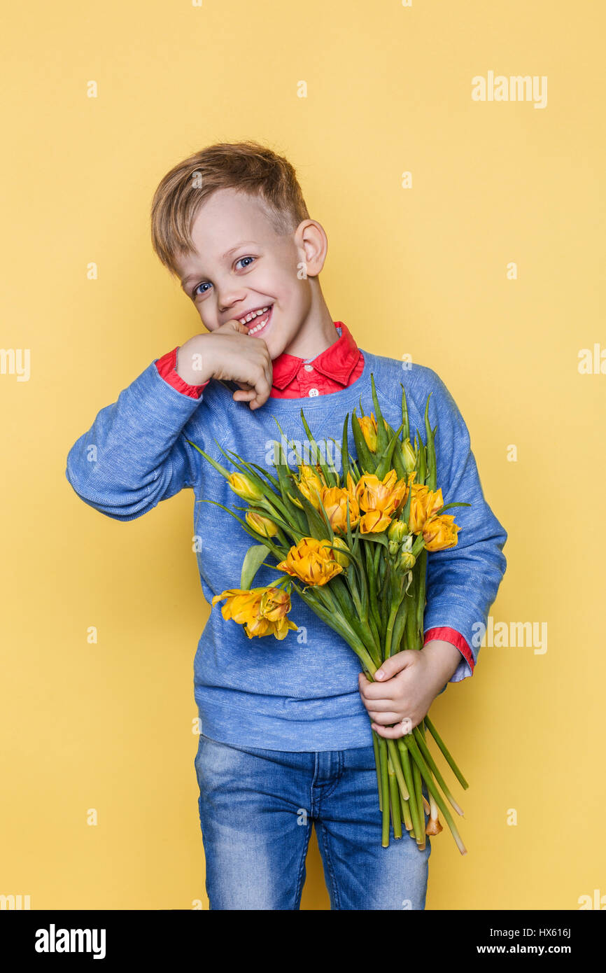 Kleines schönes Kind mit einem Strauß Tulpen. Sohn macht Mutter Blumen zum Frauentag, Muttertag. Geburtstag. Zum Valentinstag. Frühling. Stockfoto