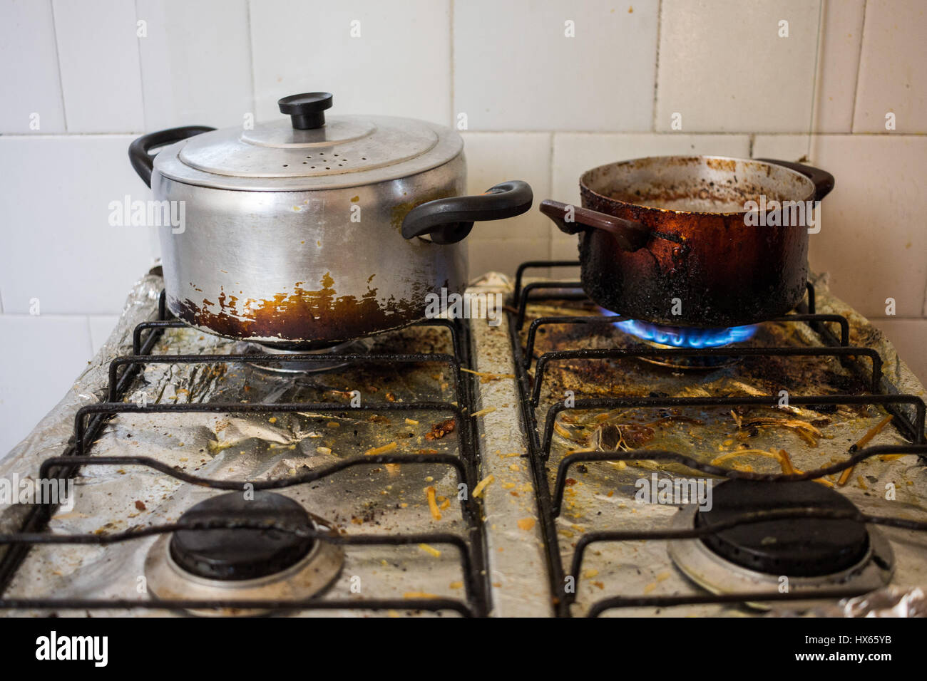 Schmutzige Pfannen auf dreckigen Herd, ungesunde Essgewohnheiten mit Braten darstellt. Stockfoto