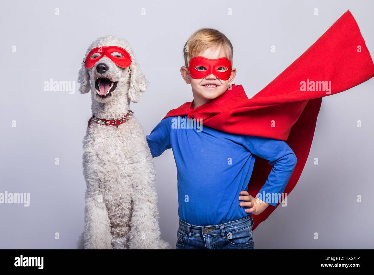 Hübsche kleine Superman mit Hund. Superheld. Halloween. Studio-Porträt auf weißem Hintergrund Stockfoto