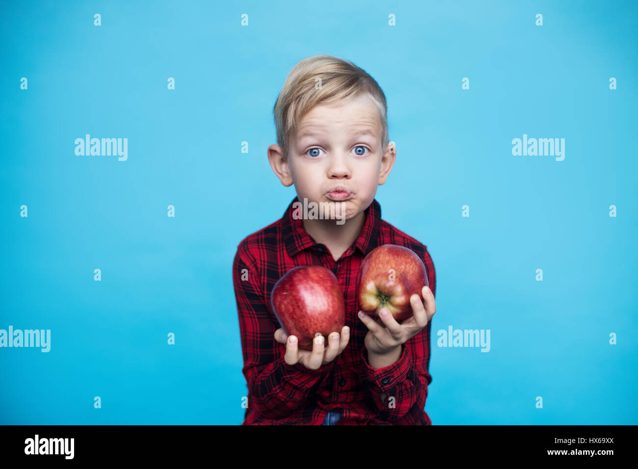 Schön kleines Kind mit Früchten. Studio-Porträt über blauem Hintergrund Stockfoto
