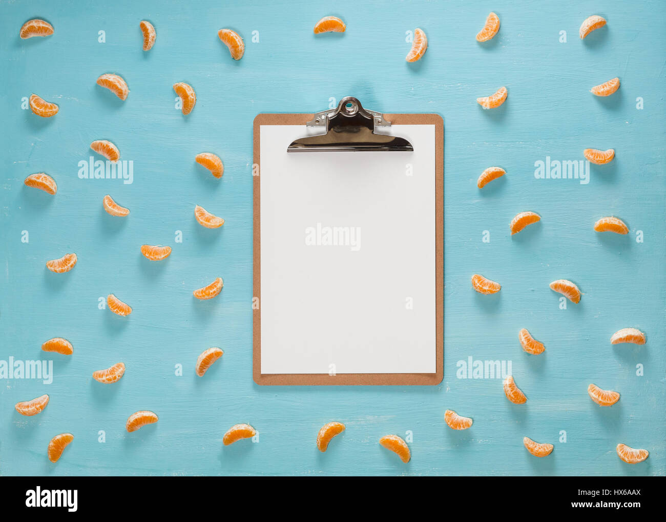 Leere Zwischenablage auf Pastell blau Tisch mit Zitrusfrüchten Mandarine Scheiben, minimalistischen Stil, flach zu legen. Stockfoto