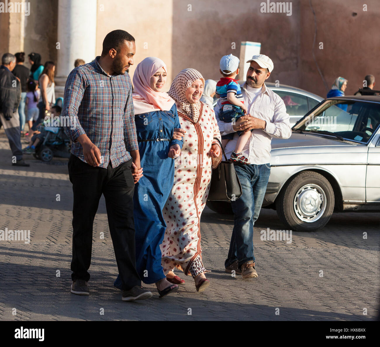 Meknès, Marokko.  Zwei Paare, überqueren die Straße an der Bab Mansour.  Frauen in zeitgenössische konservative Kleidung, Männer in westlicher Kleidung. Stockfoto