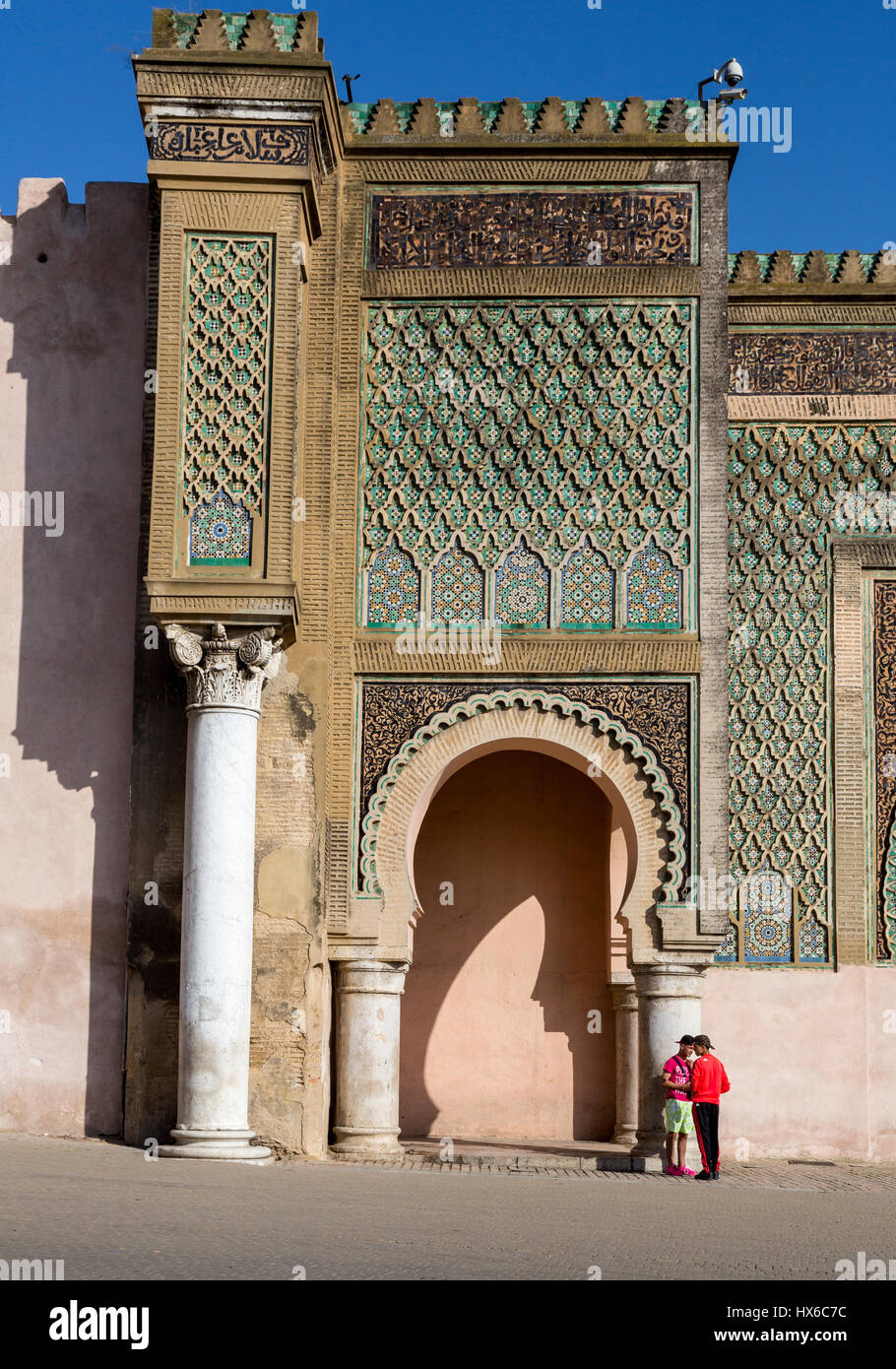 Meknès, Marokko.  Zwei junge Männer stehen vor der Bab Mansour, erbaut 1672-1732. Stockfoto