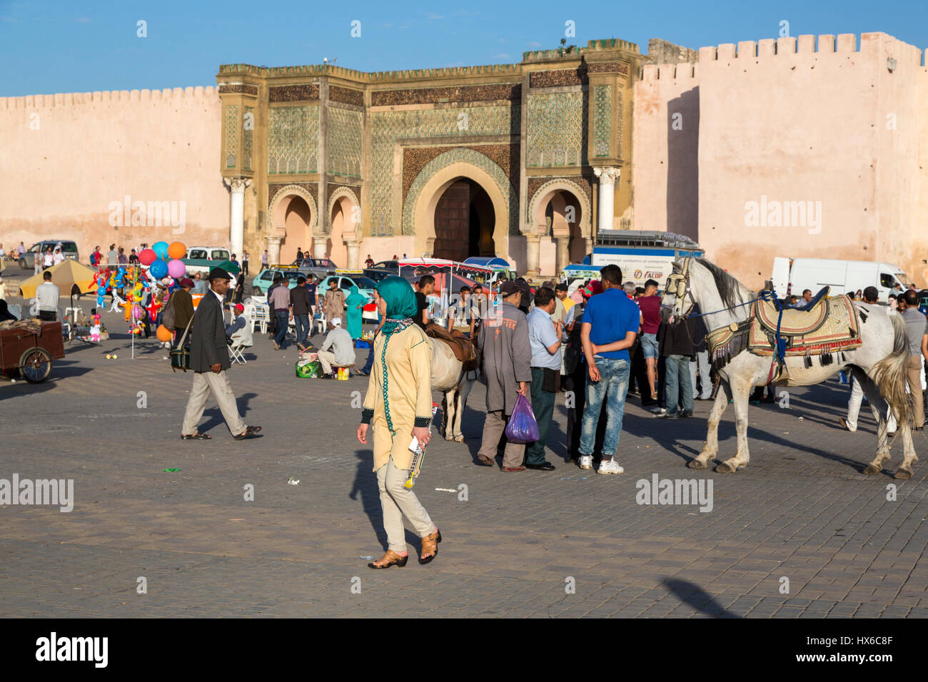 Meknès, Marokko.  Menschen in dem Ort Hedime, Bab Mansour im Hintergrund.  Das Pferd ist für die Fahrgeschäfte für Kinder. Stockfoto