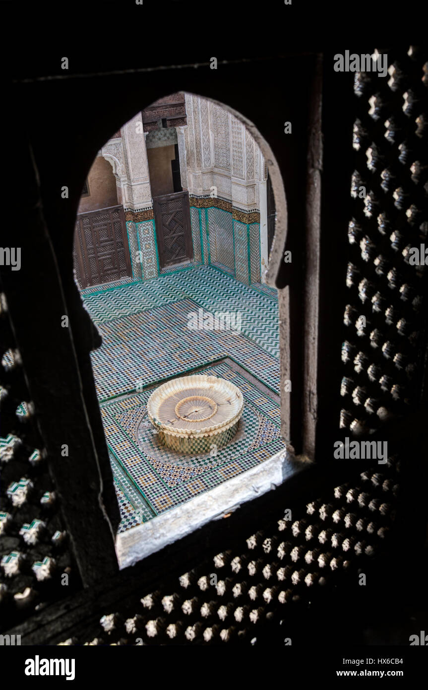 Meknès, Marokko.  Madersa Bou Inania.  Blick auf Hof Brunnen durch ein Student Obergeschoss Fenster. Stockfoto