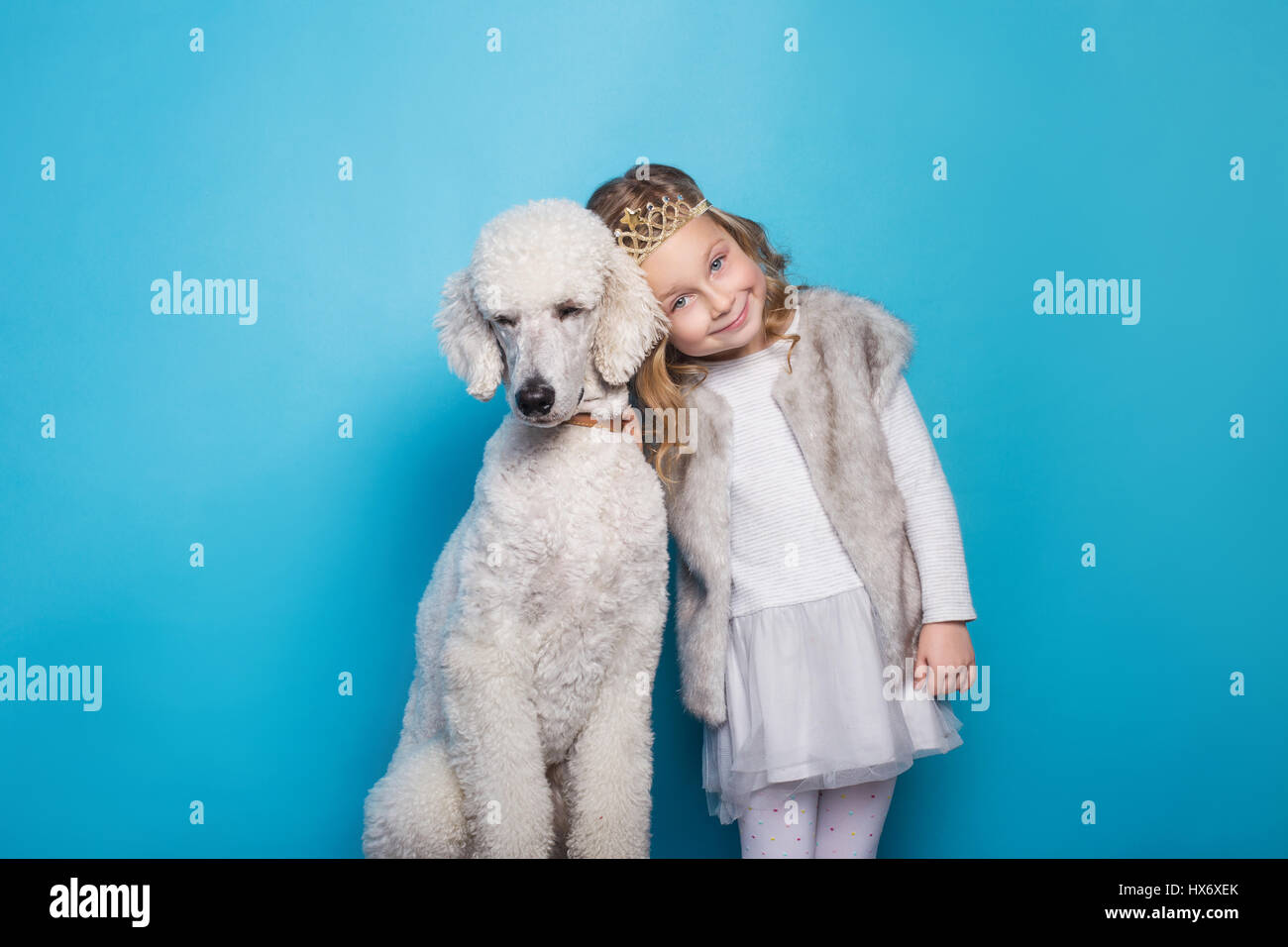 Schöne kleine Prinzessin mit Hund. Freundschaft. Haustiere. Studio-Porträt über blauem Hintergrund Stockfoto