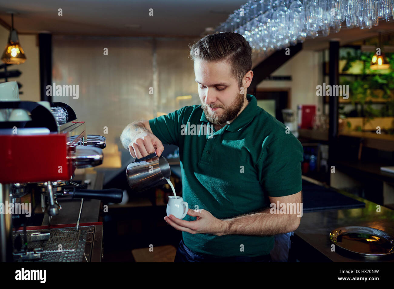 Das Barkeeper Barista gießt heißen Milch in ein Glas in bar-café Stockfoto
