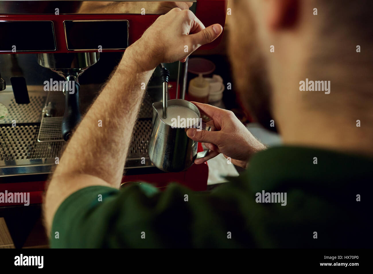 Barkeeper, Barista macht heißen Milch in einer Kaffeemaschine hinter der Stockfoto