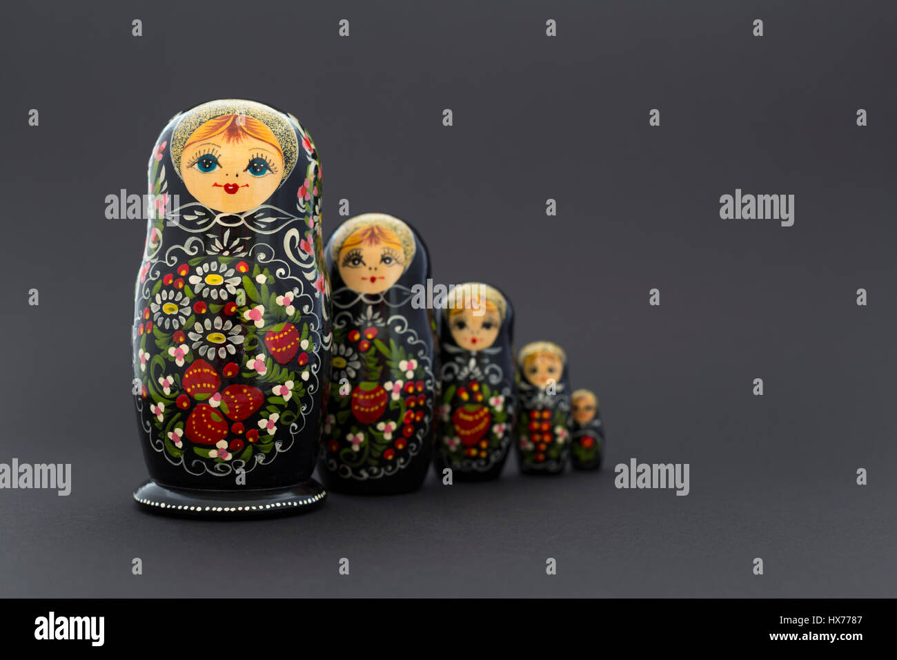 Schöne schwarze russische Verschachtelung Puppen (Matroschka Puppen) mit weißen, grünen und roten Anstrich vor dunklem Hintergrund Stockfoto