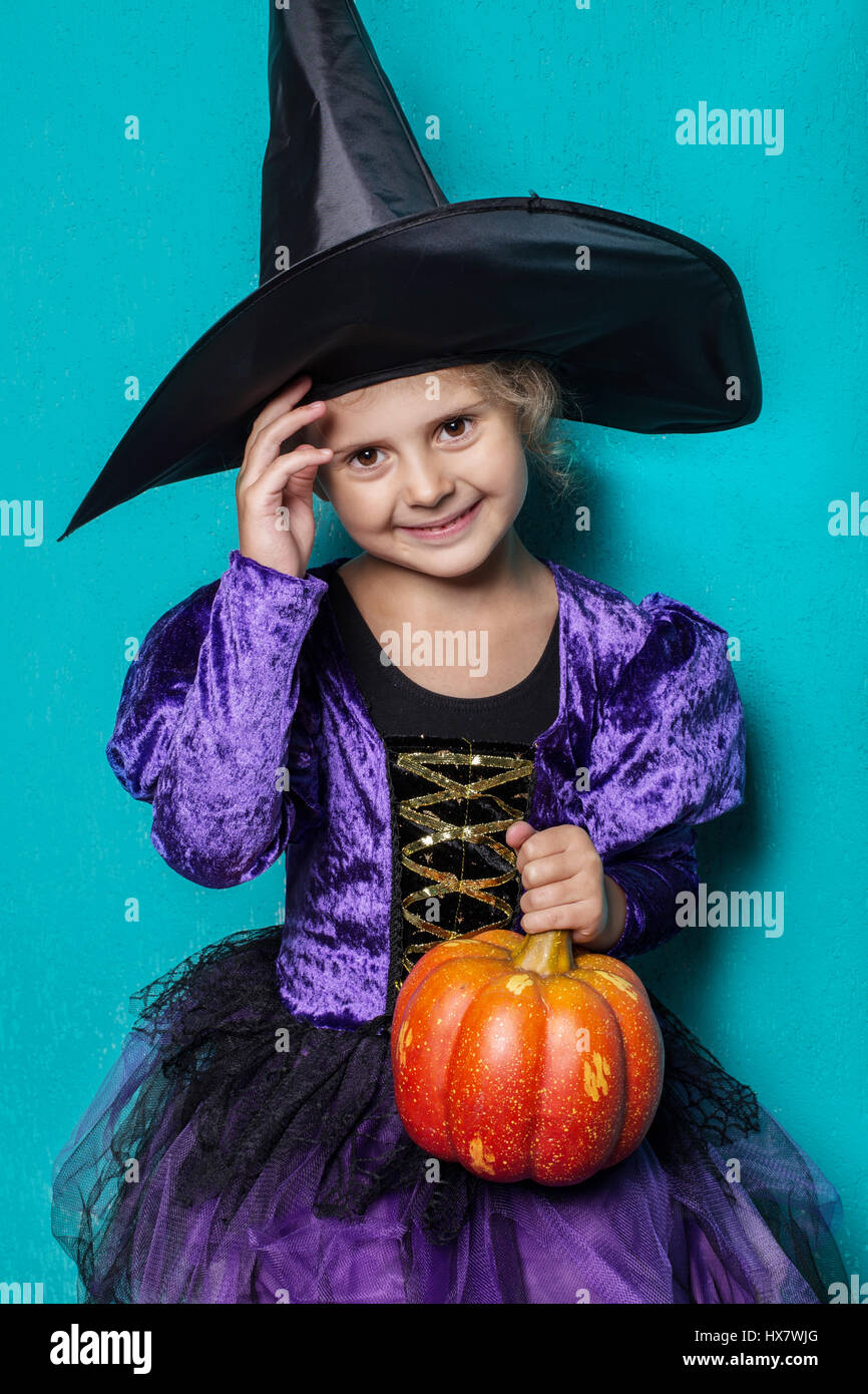 Porträt von kleinen Mädchen in schwarzen Hut und Kleidung mit Kürbis-Hexe. Halloween. Fee. Geschichte. Studio-Porträt auf blauem Hintergrund Stockfoto