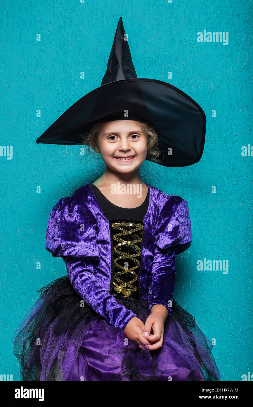 Porträt von kleinen Mädchen in schwarzen Hut und Kleidung mit Kürbis-Hexe. Halloween. Fee. Geschichte. Studio-Porträt auf blauem Hintergrund Stockfoto