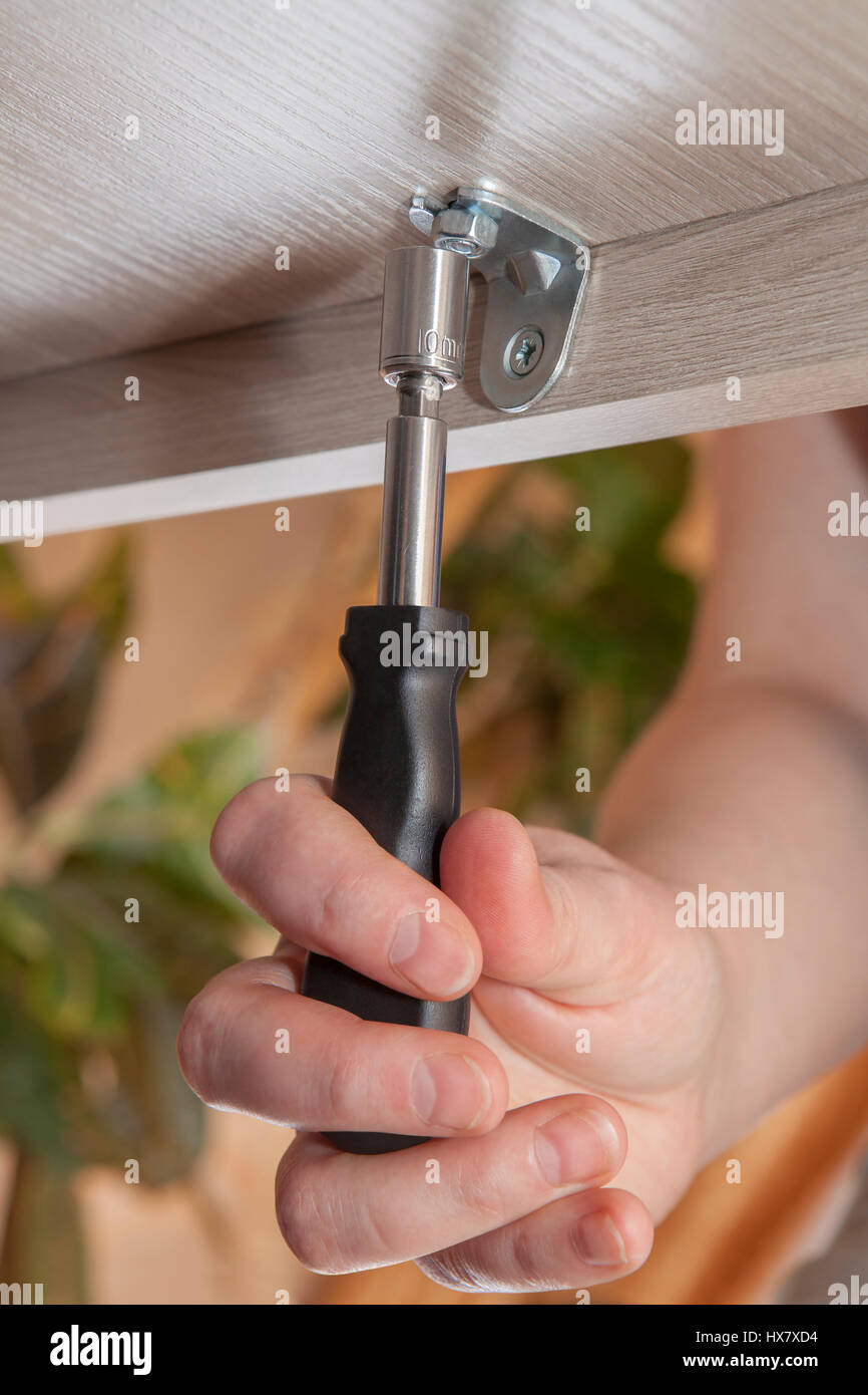 Nahaufnahme einer menschlichen Hand mit hex Truss Rod Anpassung Schraubenschlüssel ziehen Sie die Mutter, Montage von Möbeln zu Hause. Stockfoto