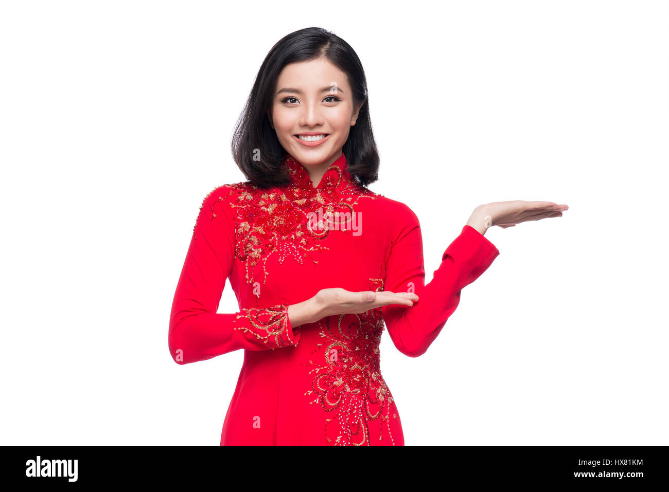 Bezaubernde vietnamesische Frau in roten Ao Dai Tracht präsentieren etwas. Stockfoto