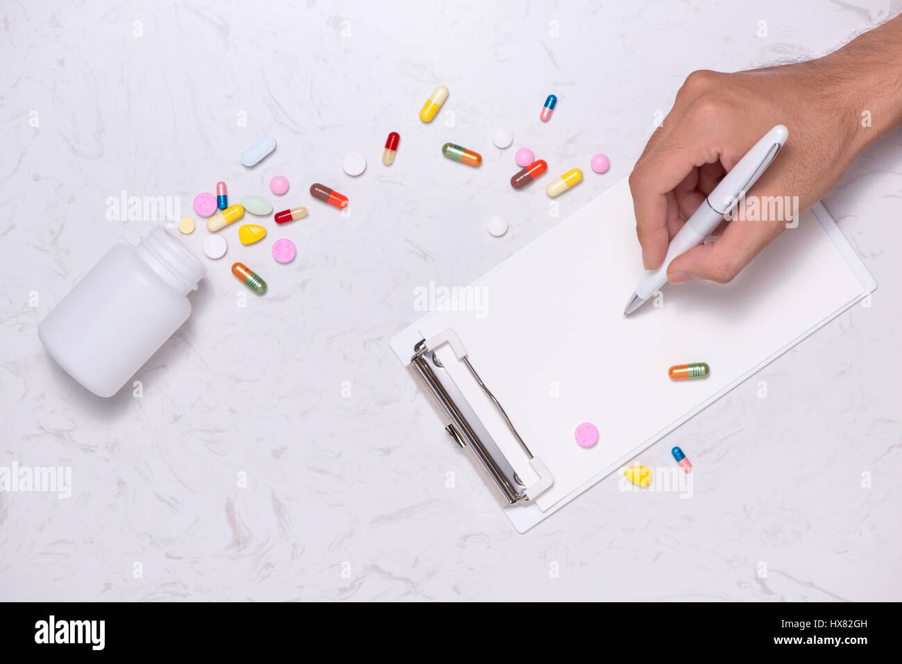 Geöffnete Medizinfläschchen und verschüttete, Kapseln mit textfreiraum auf Tisch. Stockfoto