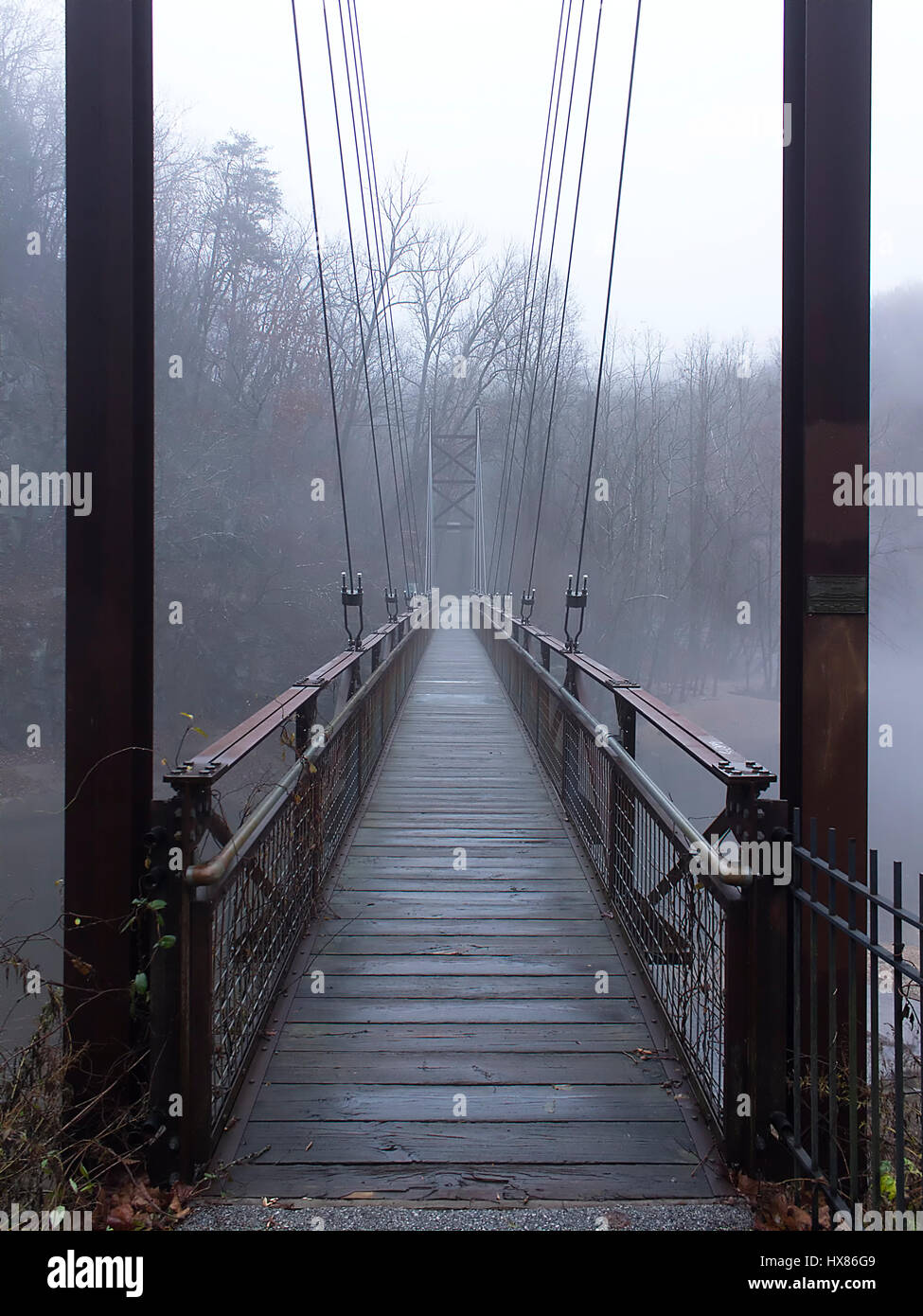 Fußgänger-Hängebrücke über den Fluss mit Nebel Stockfoto