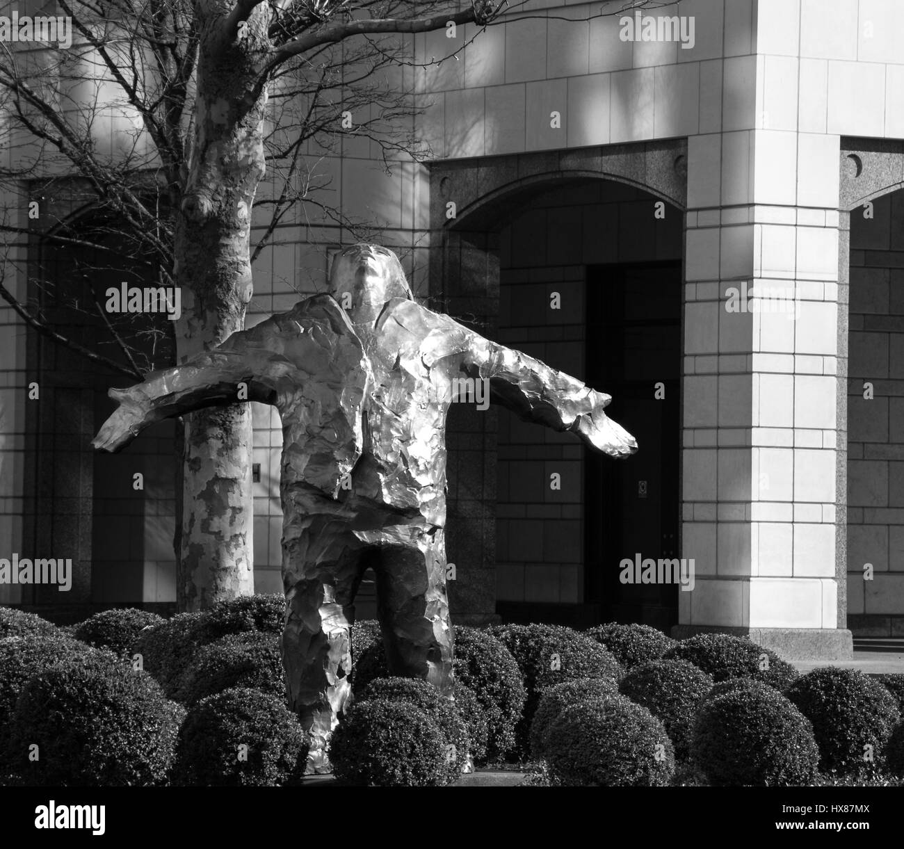 Mann mit Armen ausgestreckten Skulptur von Giles Penny, Canary Wharf, London, UK in Monochrom Stockfoto