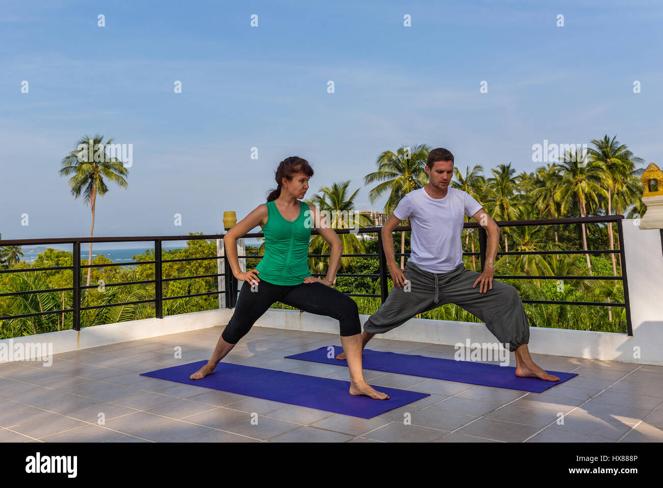 Yoga-Lehrer führt Klassen mit der Frau auf dem Balkon des Hotels Stockfoto