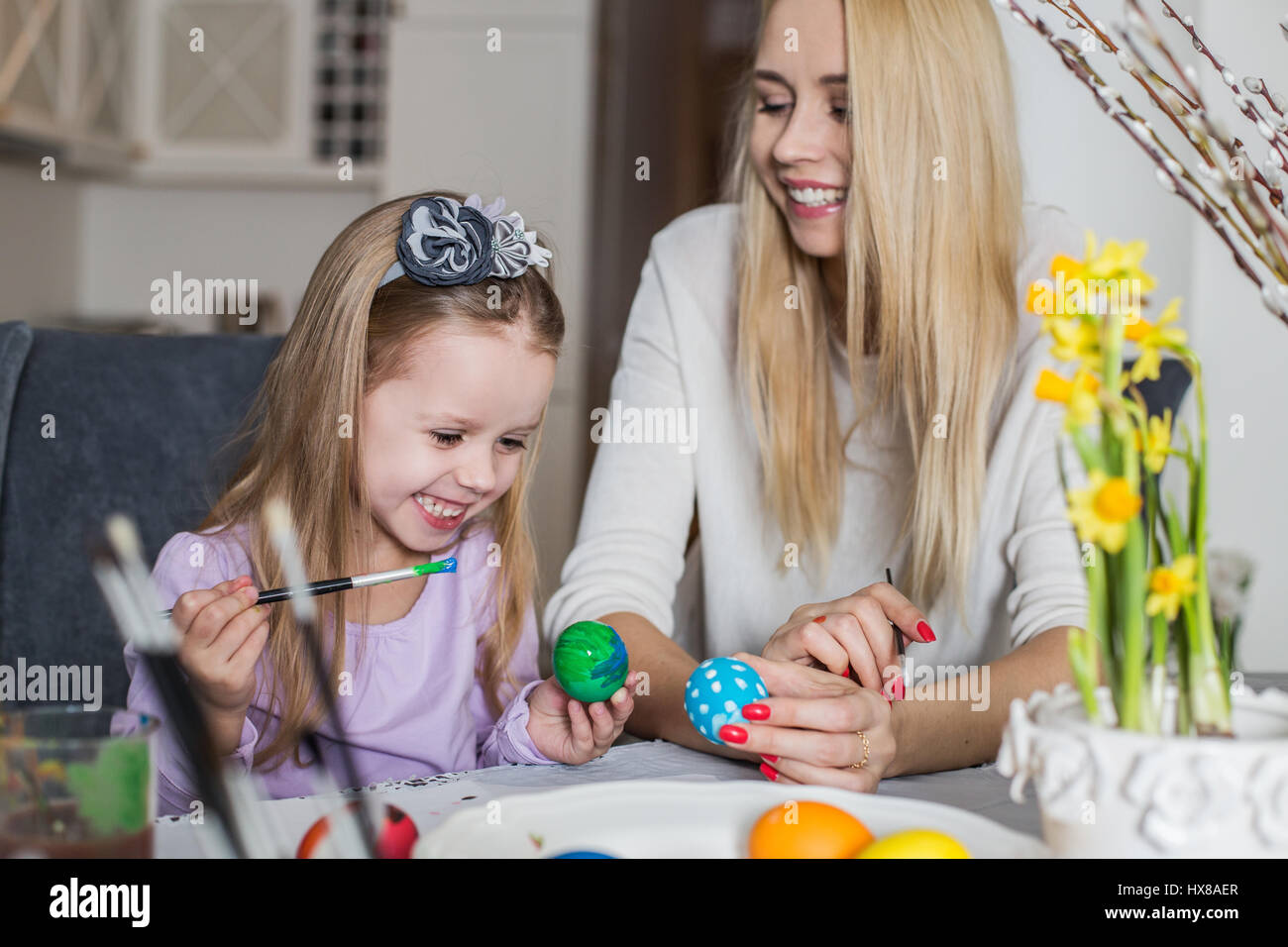 Ostern, Familie, Urlaub und Kind Konzept - Nahaufnahme von kleinen Mädchen und seine Mutter Färbung Eiern zu Ostern Stockfoto