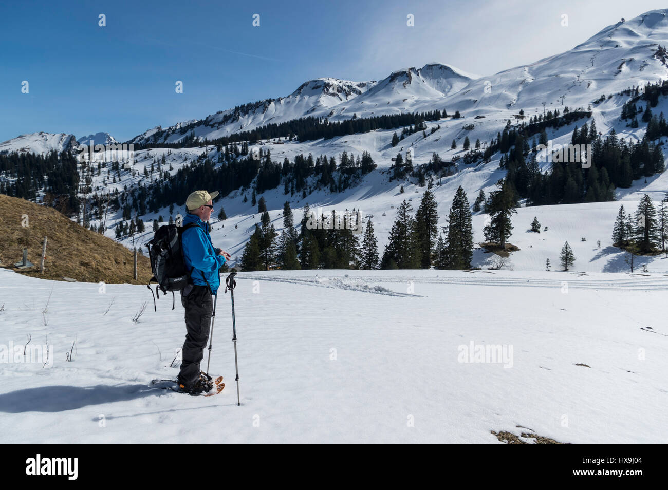 Mittleren Alters männlichen Schneeschuh-Wanderer in den Schweizer Alpen, genießen die Sonne und das Panorama auf die umliegenden Berge. Stoos, Kanton Schwyz, Schweiz. Stockfoto