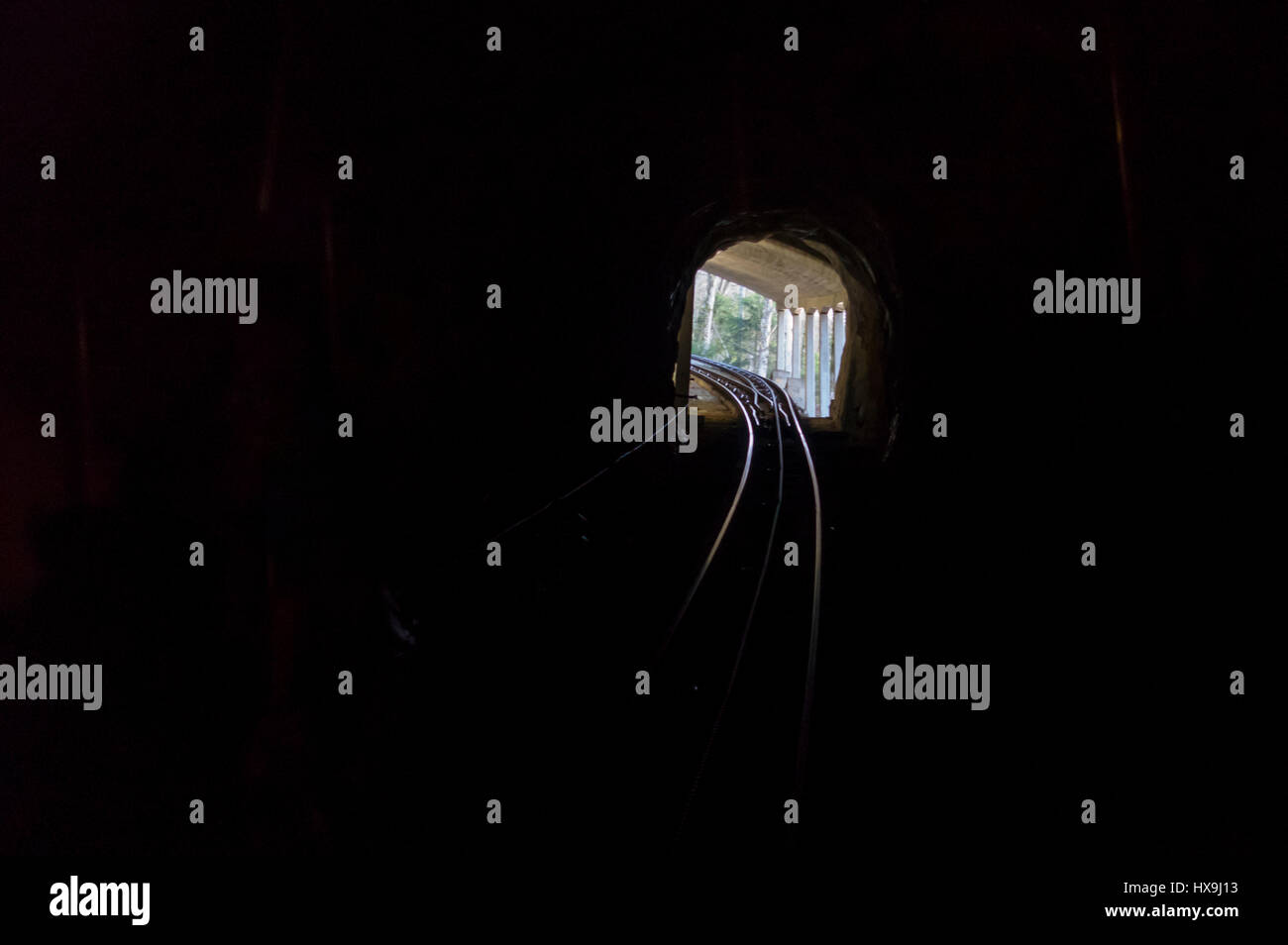 Dunklen, nicht beleuchteten Eisenbahntunnel der alten steile Standseilbahn Schlattli bis Stoos, Zentralschweiz. Licht am Ende des Tunnels. Stockfoto