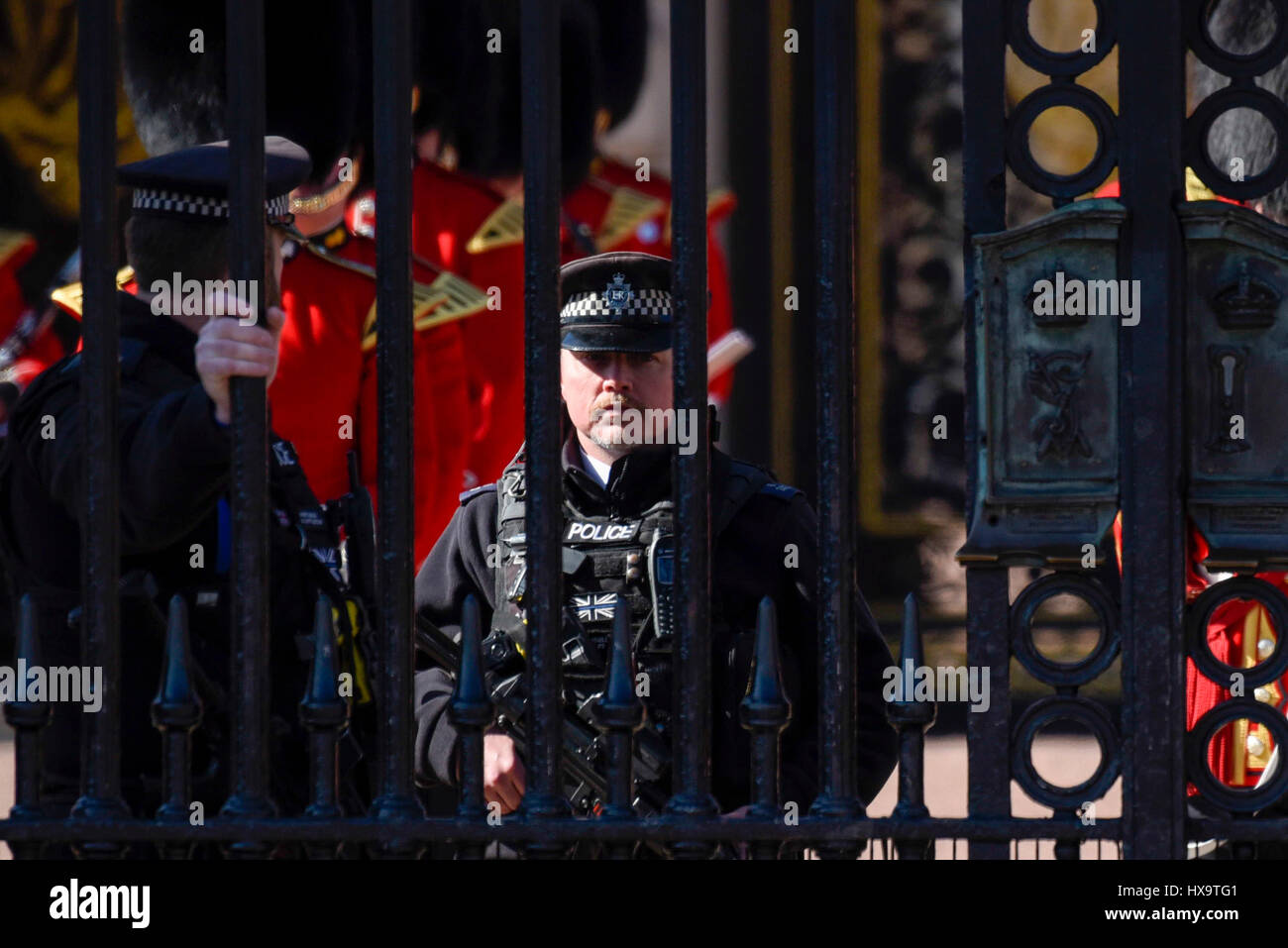 London, UK.  26. März 2017.  Ein bewaffneter Polizist sieht man hinter den Toren des Buckingham Palace.  Eine erhebliche Polizeipräsenz ist im Ort für das Ändern der Wachablösung.  Mit der Ankunft von British Summer Time heute, ändern der Foot Guards ihre grauen Wintermantel große in ihren legendären rot und Gold Tuniken. Bildnachweis: Stephen Chung / Alamy Live News Stockfoto