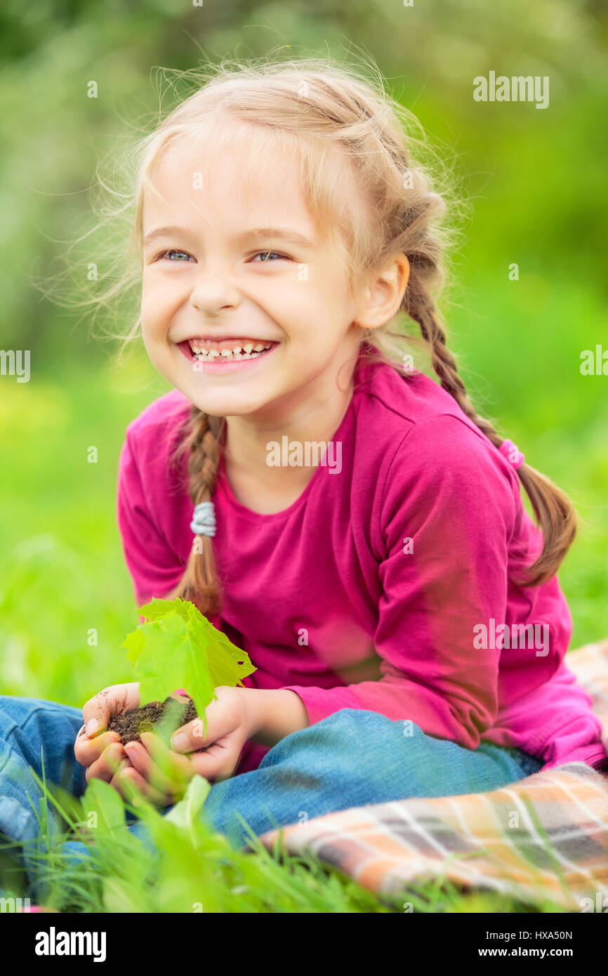 Kleines Mädchen, kleine grüne Pflanze in ihren Händen hält Stockfoto