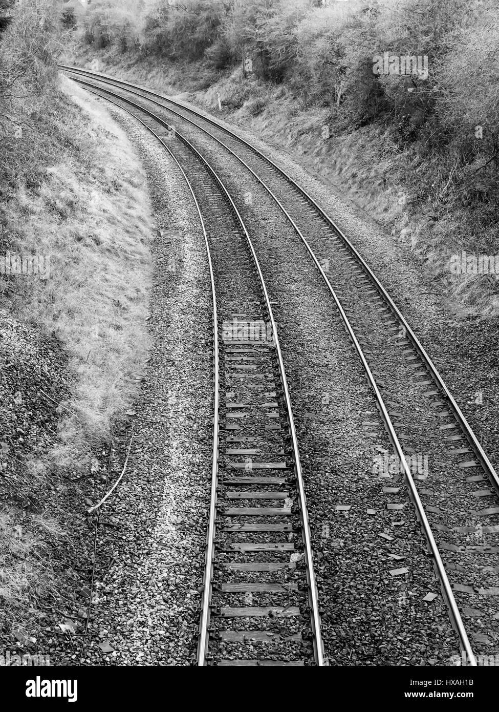 Zwei normalspurigen Eisenbahnstrecken auf einer Kurve in eine Beschneidung gerendert in schwarz / weiß Stockfoto
