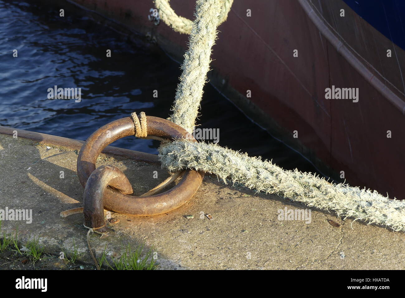 Festmacher Seil durchlaufen eine rostige Stahlring mit Schiffsrumpf auf Hintergrund Stockfoto