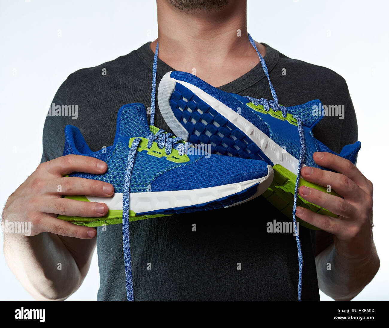 Sportschuhe hängen Mann Hals auf Schnürsenkel. Bunte Laufschuhe im Sport Mannhände Stockfoto