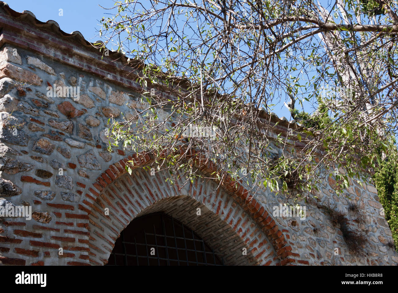 Fragment der restaurierten mittelalterlichen Moschee mit Bogen gebaut aus Stein und Ziegel mit Ästen in Rahmen Stockfoto