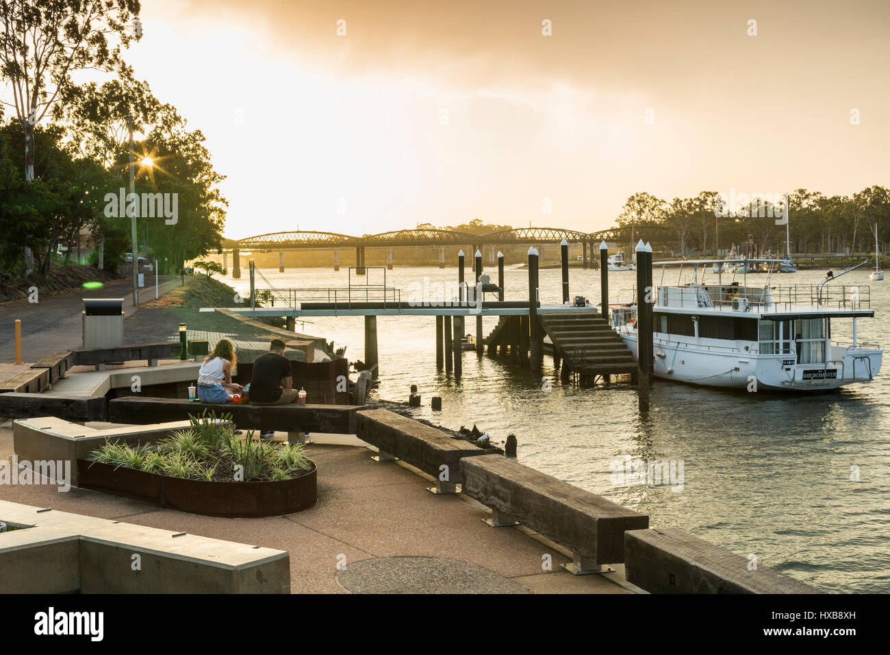 Paar entspannend mit Burnett-Brücke über dem Fluss entlang.  Bundaberg, Queensland, Australien Stockfoto