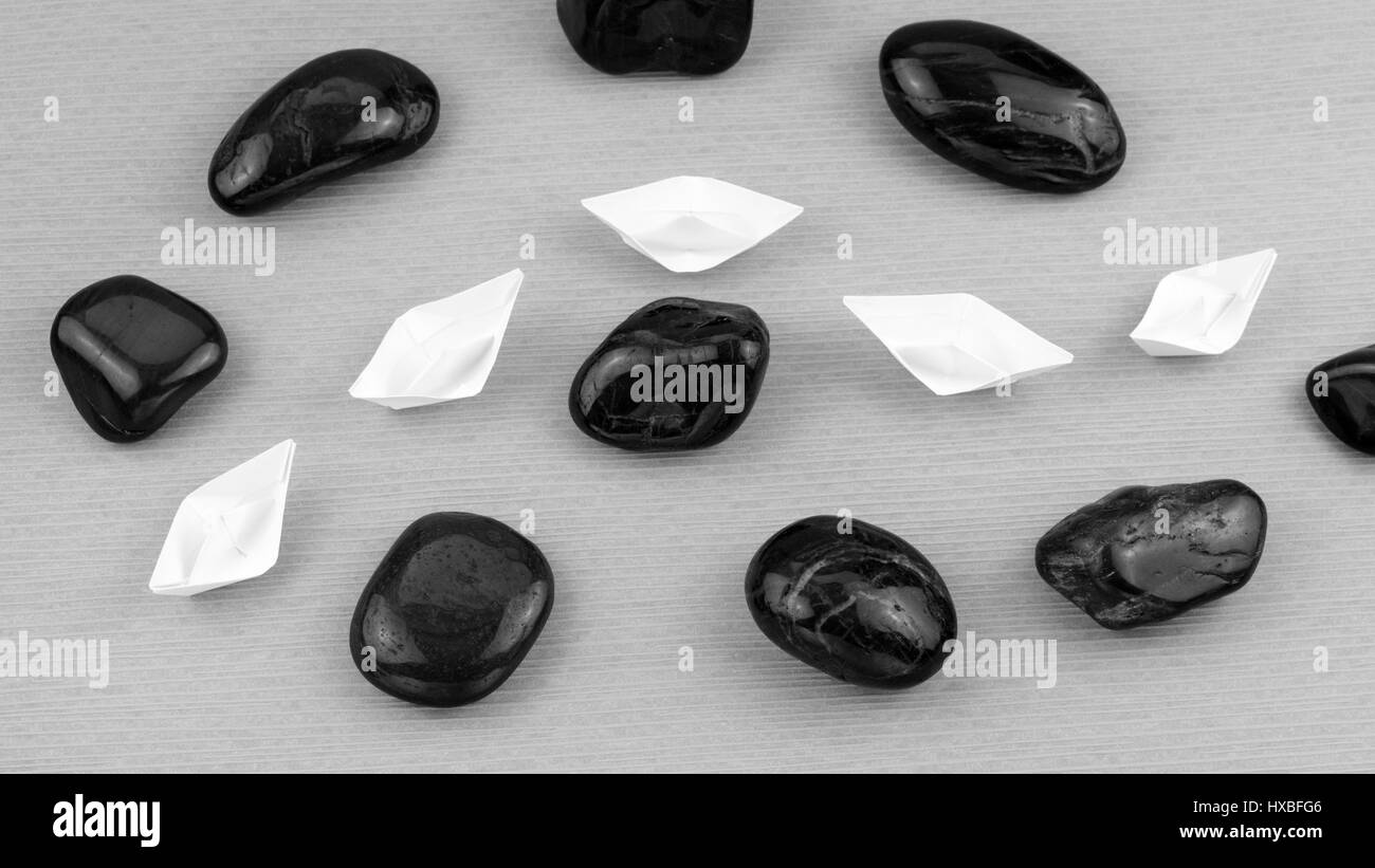 White Paper Boote in Sigle-Datei zwischen abstrakten Rock Steinen. Schwarz / weiß Stockfoto