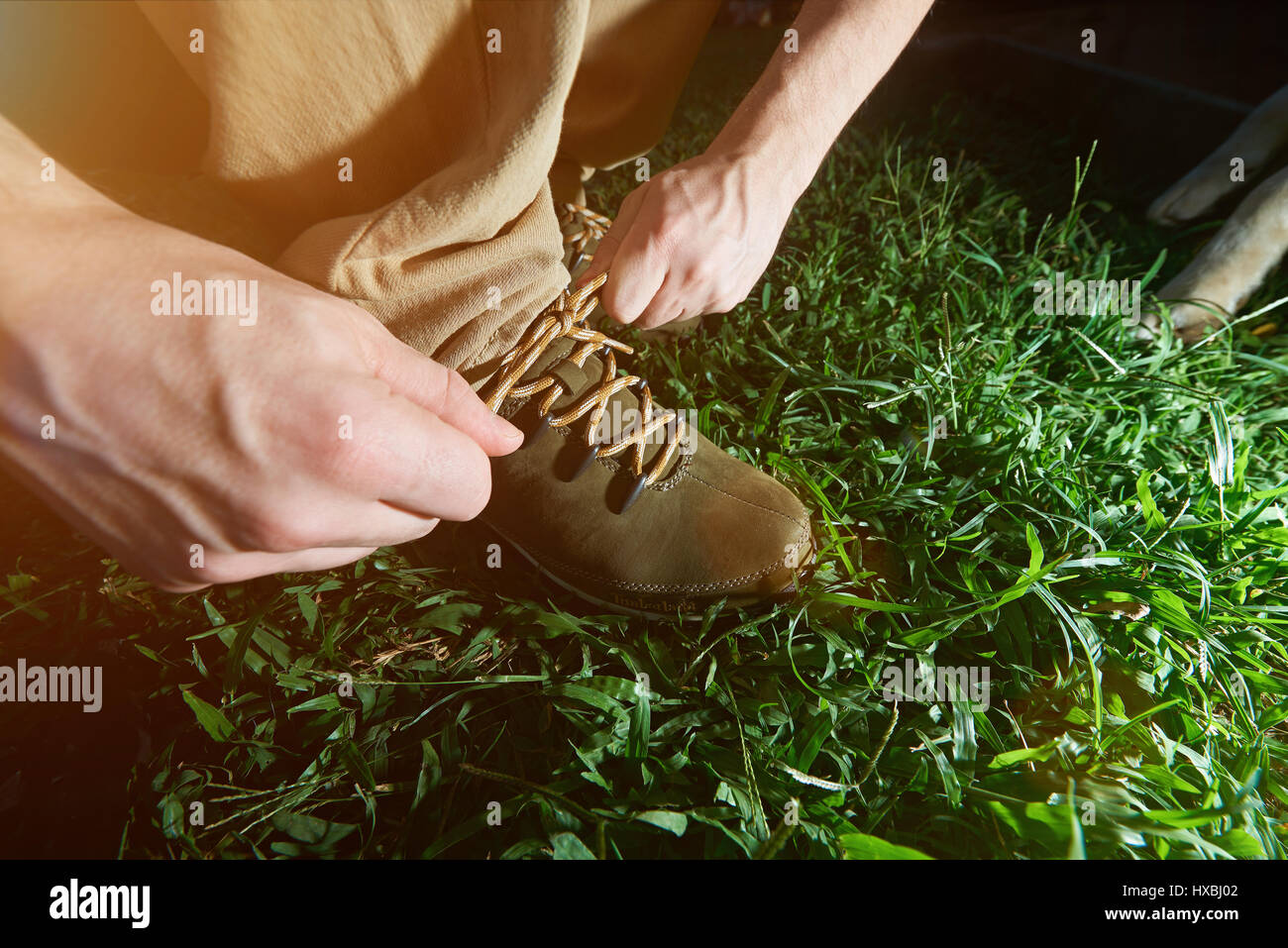 Nahaufnahme der Bindung Wandern Schuhe stehen auf dem grünen Rasen. Mann seine Schnürsenkel zu binden Stockfoto