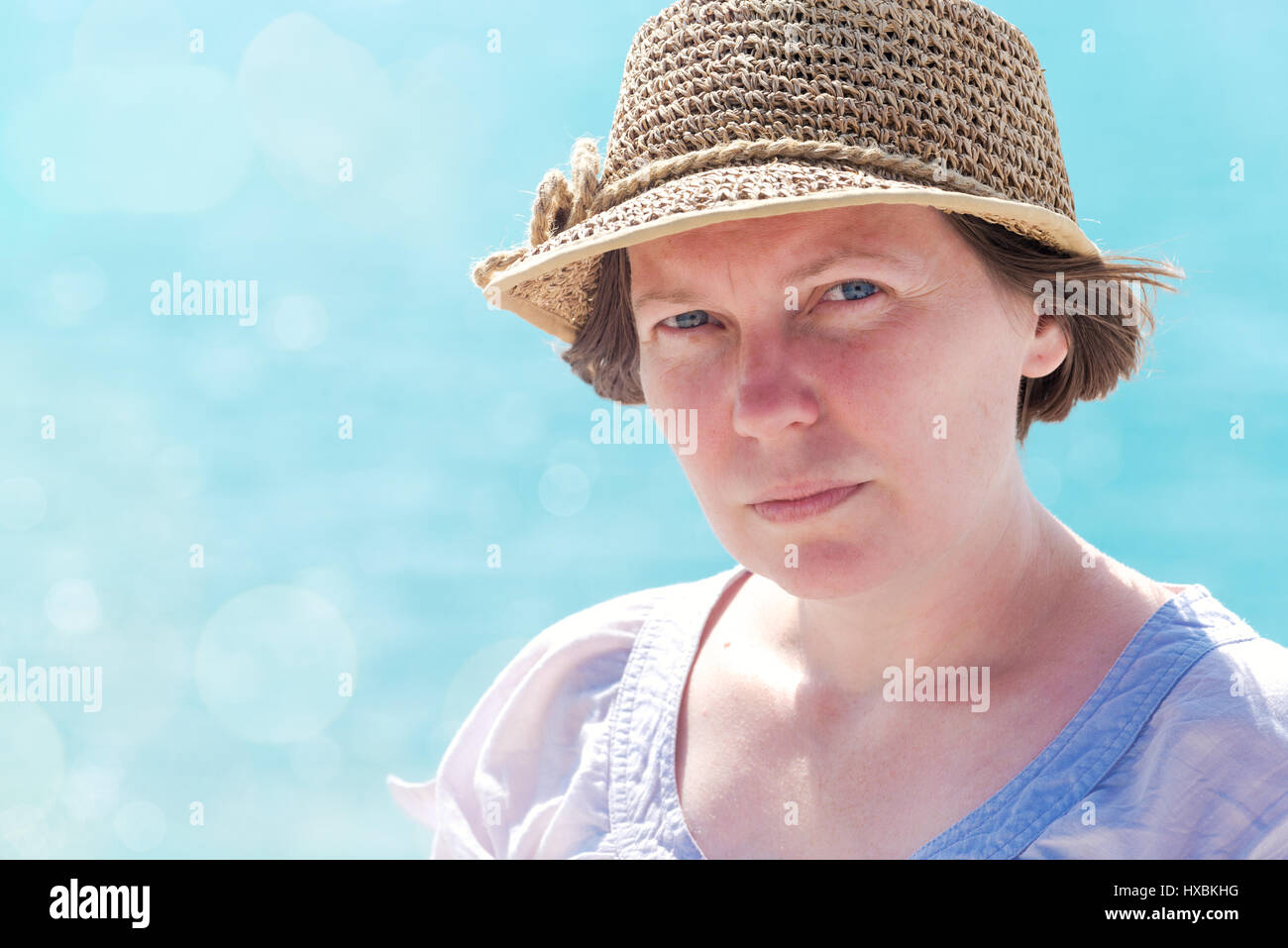 Porträt von Ernst weibliche Touristen mit Strohhut am Meer an sonnigen Tag Stockfoto