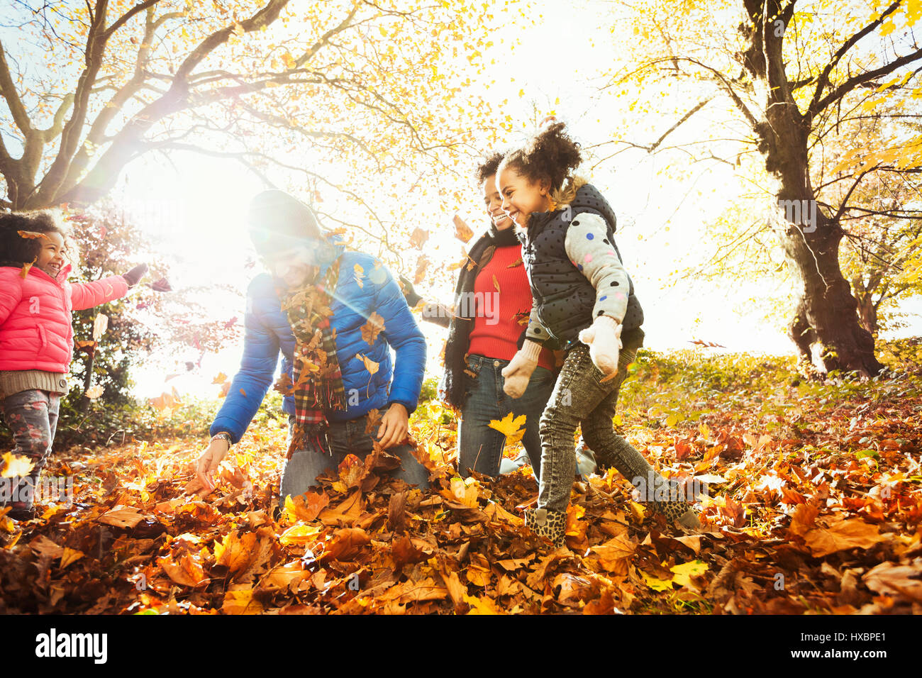 Verspielte junge Familie spielen im Herbst Blätter im sonnigen park Stockfoto